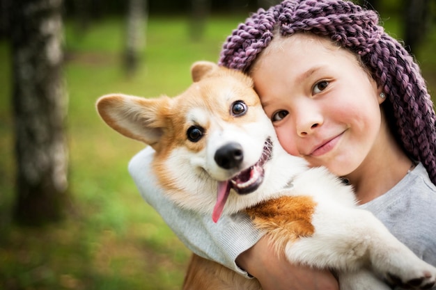 Hermosa chica camina con un cachorro en un parque de verano