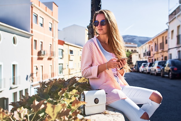 Foto hermosa chica caminando y escribiendo mensajes en un teléfono móvil en la calle