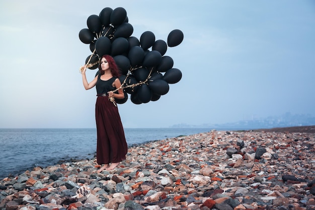 Hermosa chica caminando con globos negros