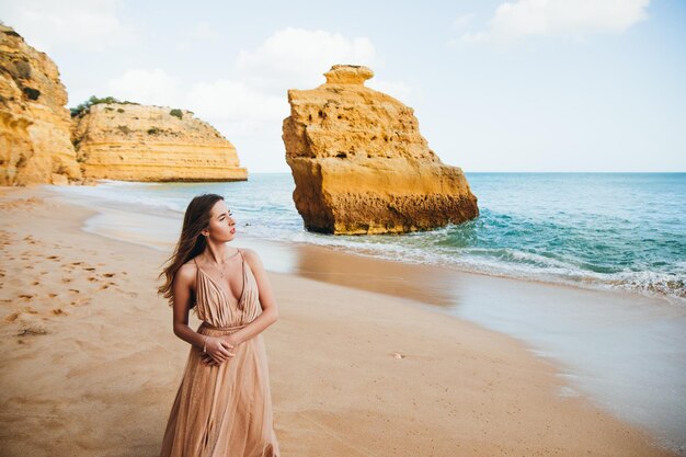 Hermosa chica caminando por la playa al atardecer, concepto de libertad