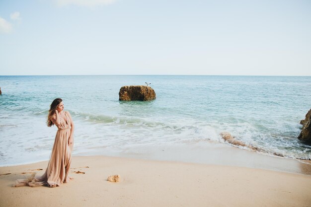 Hermosa chica caminando por la playa al atardecer, concepto de libertad