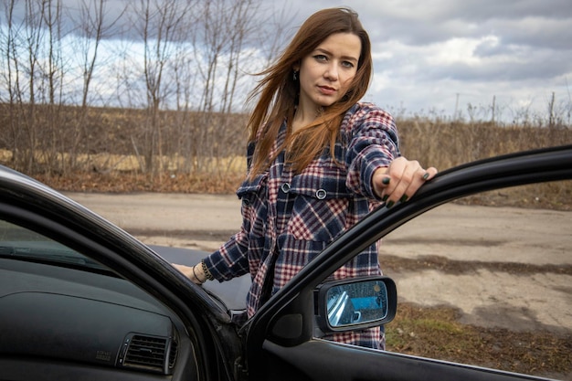 Hermosa chica en una camisa cerca del coche