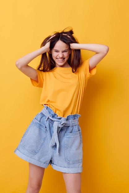 Hermosa chica en una camiseta amarilla emociones verano estilo fondo amarillo