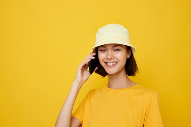 Hermosa chica camiseta amarilla y sombrero estilo de verano con teléfono Estilo de vida inalterado