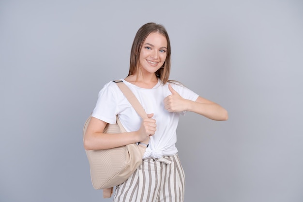 Una hermosa chica con camiseta blanca con mochila en la espalda estudiante sonríe