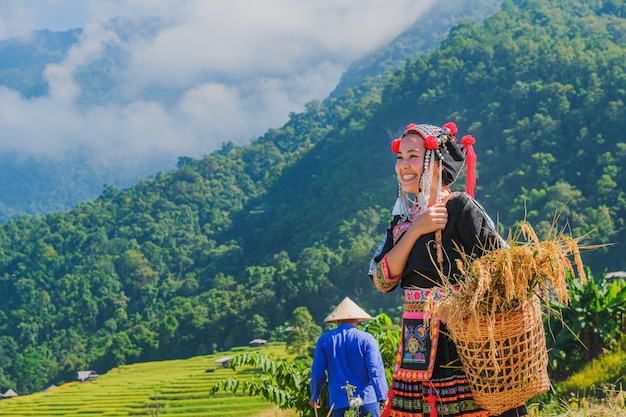 Hermosa chica campesina con paja en campos de arroz en el norte de Tailandia