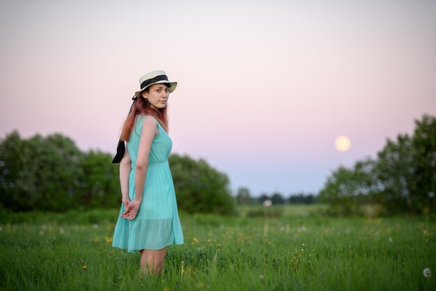 Hermosa chica en el campo contra el cielo con la luna