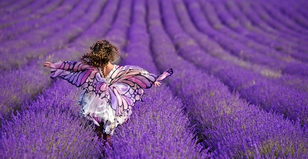 Foto hermosa chica en el campo de lavanda. chica con el pelo rizado. mariposa