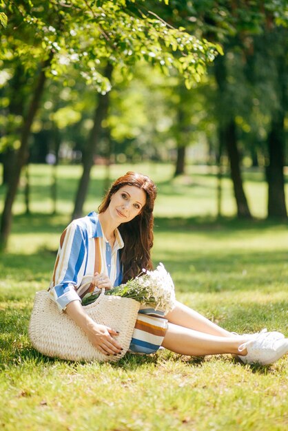 Hermosa chica con una canasta de flores blancas en el parque