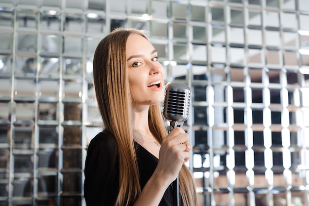 Hermosa chica cantante. Mujer de belleza con micrófono. Cantante modelo glamour. Canción de karaoke.