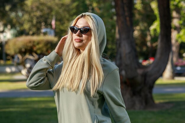 Una hermosa chica con capucha y de pie en el parque