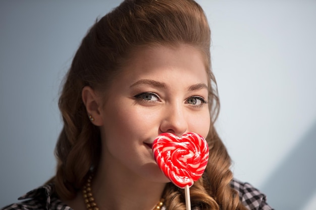 Hermosa chica con un caramelo rojo en forma de corazón