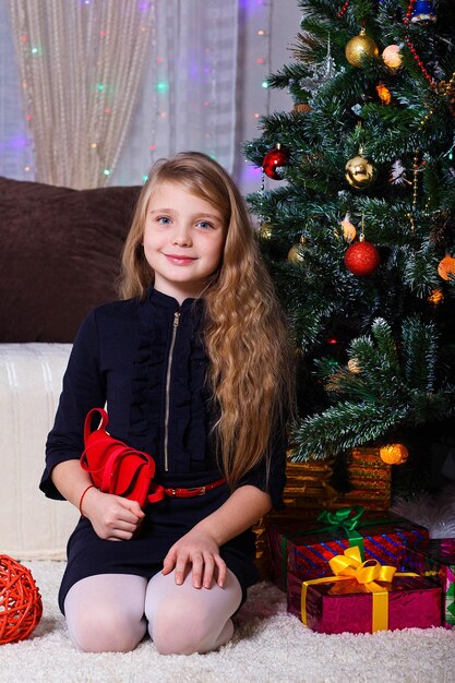 Hermosa chica caucásica de cabello blanco posando cerca de la chimenea Estado de ánimo de Navidad y año nuevo