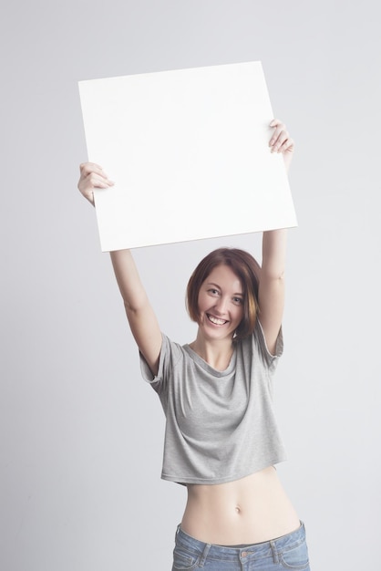 Foto hermosa chica caucásica sosteniendo un cartel en blanco para texto o anuncio