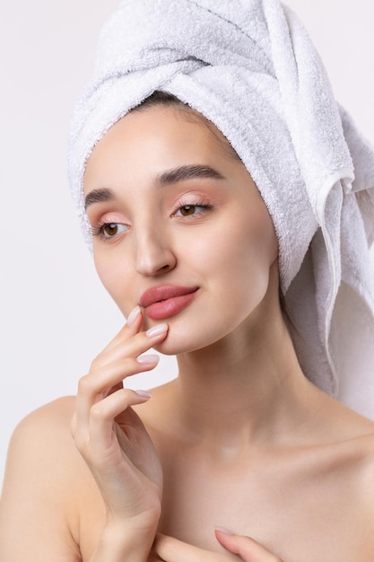 Hermosa chica con cejas gruesas y piel perfecta en una toalla de fondo blanco en la foto de belleza de la cabeza