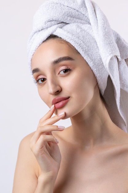 Hermosa chica con cejas gruesas y piel perfecta en una toalla de fondo blanco en la foto de belleza de la cabeza