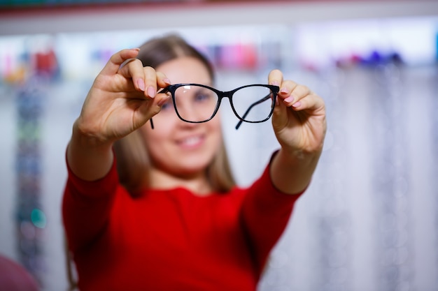 Hermosa chica en un centro de oftalmología recoge gafas para corregir la visión