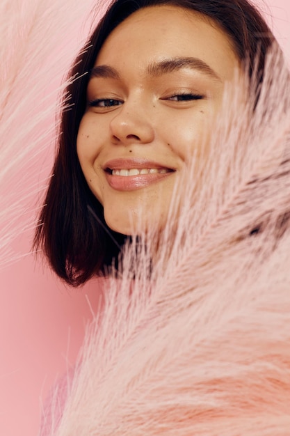 Hermosa chica en un chaleco rosa con plumas en las manos Estilo de vida inalterado