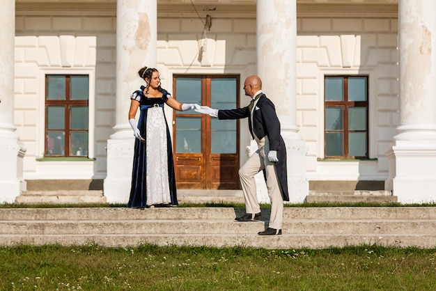 Hermosa chica con un chico con atuendo vintage en el fondo del castillo