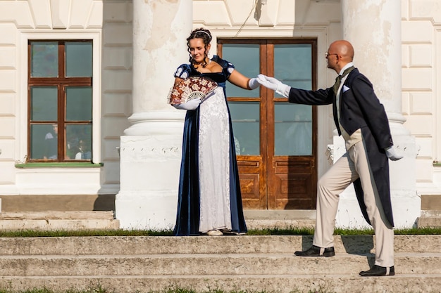 Hermosa chica con un chico con atuendo vintage en el fondo del castillo