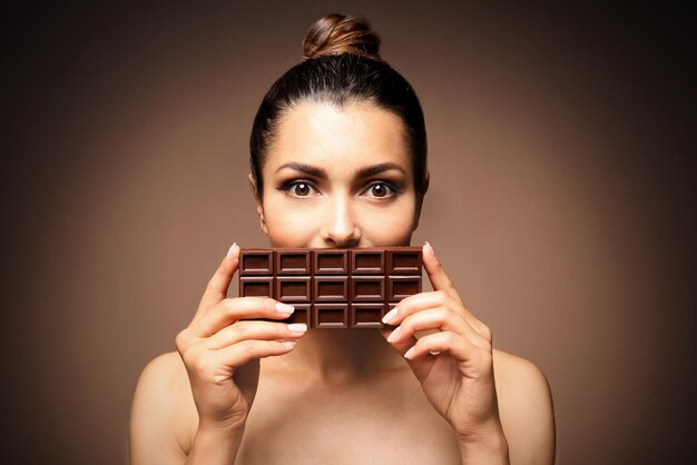 Foto hermosa chica con chocolate sobre fondo marrón