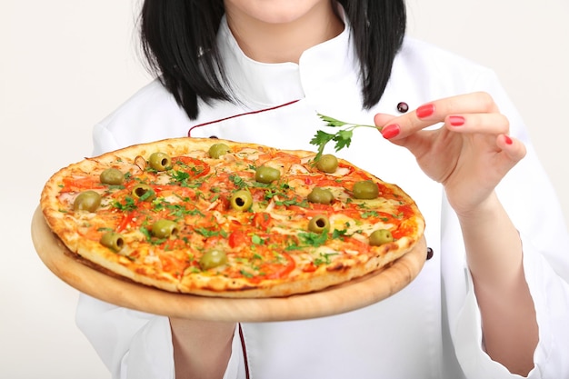 Hermosa chica cocinera con pizza aislada en blanco