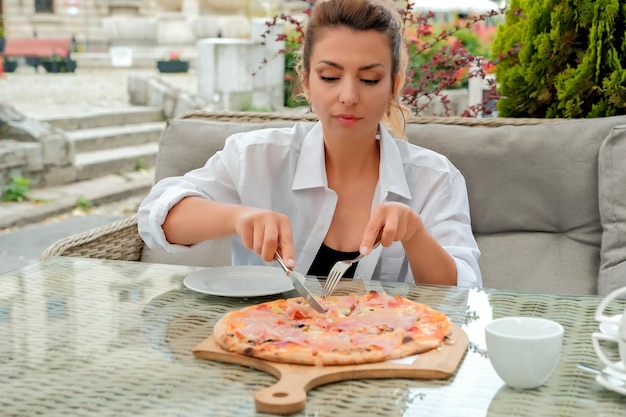 Hermosa chica come pizza en un café de la calle chica muestra diferentes emociones