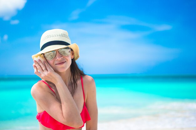 Hermosa chica con concha en manos en playa tropical