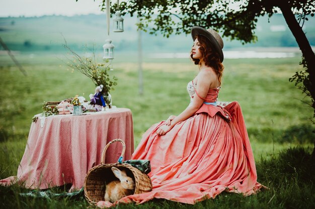 Hermosa chica con un conejo al aire libre en día de verano