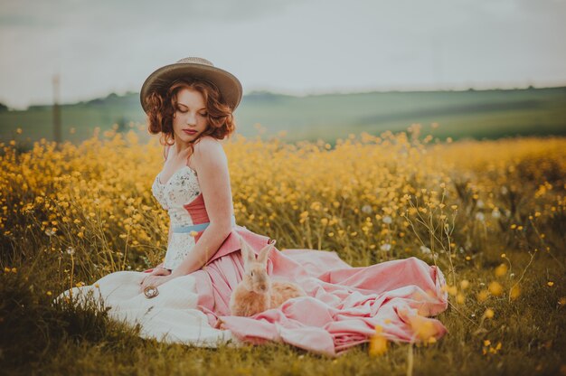 Hermosa chica con un conejo al aire libre en día de verano