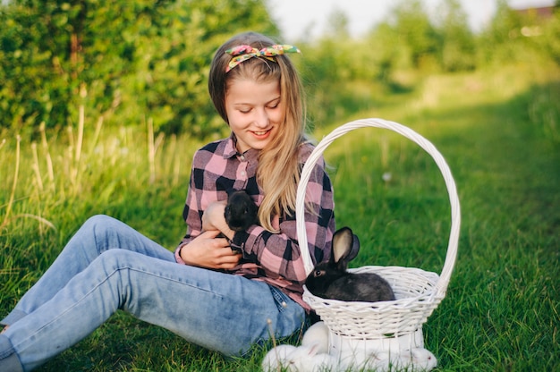 Hermosa chica con un conejo. Niña ríe y besa a un conejo. camisa de camisa y jeans. conejo de Pascua. Reír en voz alta