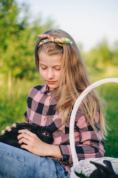 Foto hermosa chica con un conejo. niña ríe y besa a un conejo. camisa de camisa y jeans. conejo de pascua. reír en voz alta