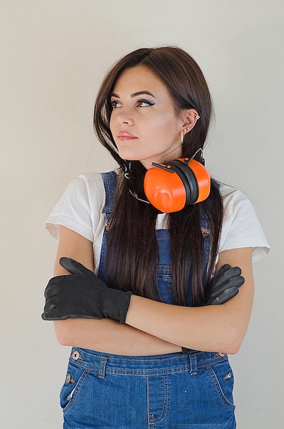 Hermosa chica constructora con auriculares protectores y guantes de construcción