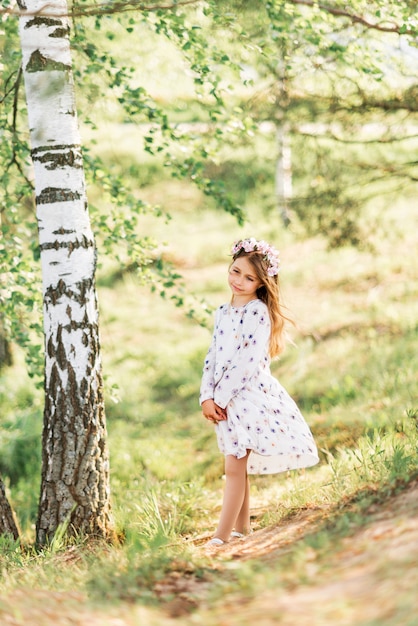 Hermosa chica con corona floral en la naturaleza