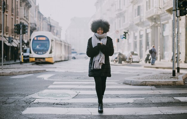 Hermosa chica con corte de pelo afro caminando por la calle