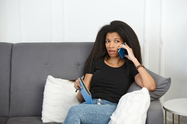 Foto una hermosa chica con un cuaderno habla en un teléfono inteligente