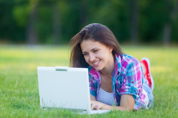 Hermosa chica con el cuaderno sobre un césped