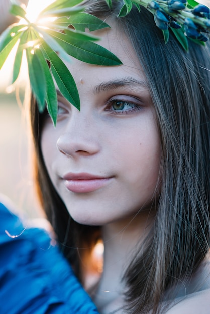 Hermosa chica cubre su rostro con hojas verdes de una flor de lupino. De cerca. Ojos grandes.