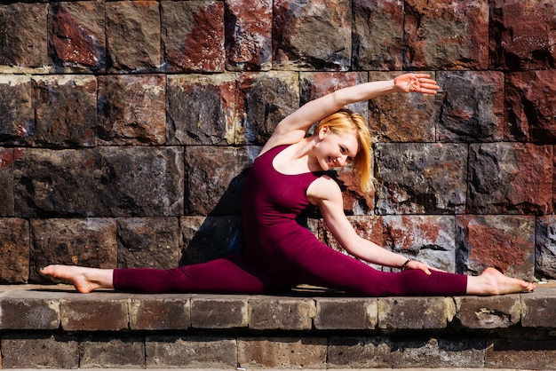 Hermosa chica dedicada al yoga en el fondo de un muro de piedra