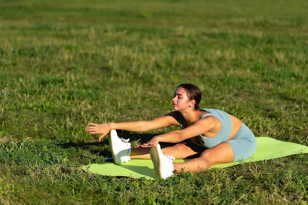 Hermosa chica deportiva practica deportes en la hierba verde en el parque de la ciudad. Extensión