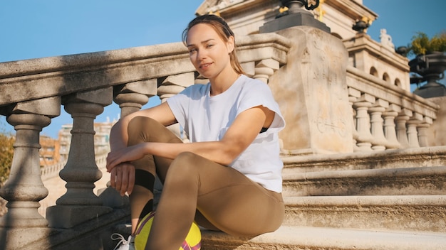 Hermosa chica deportiva sentada en las escaleras con fútbol