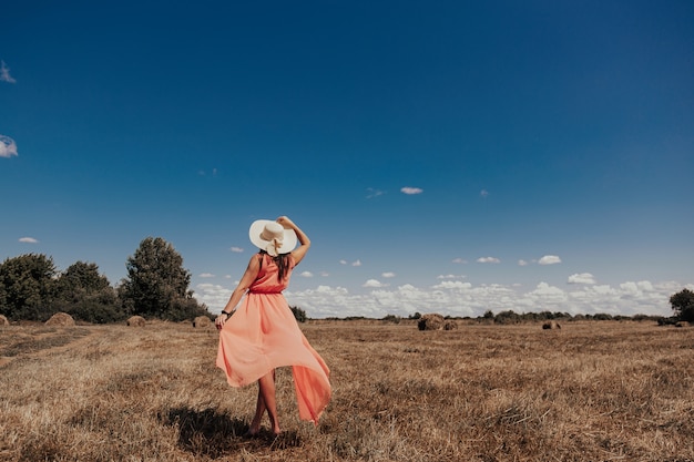 Hermosa chica descansa después del trabajo. chica en el campo con heno. Mujer cerca de una gavilla de heno en un campo. Vida rural. Vacaciones en el pueblo.