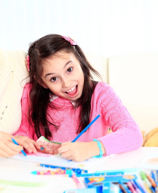 Hermosa chica dibuja con crayones y marcadores con sorpresa y alegría en su rostro.