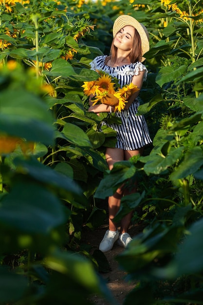 Hermosa chica disfrutando de la naturaleza en el campo de girasoles al atardecer