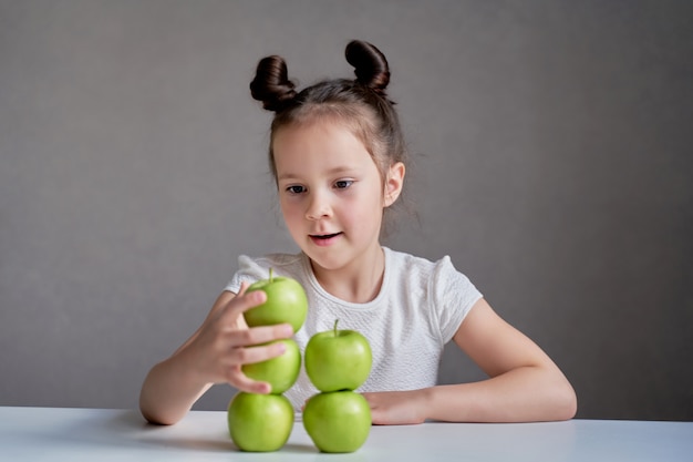 Hermosa chica divertida con manzanas verdes. Una nutrición adecuada es la salud.