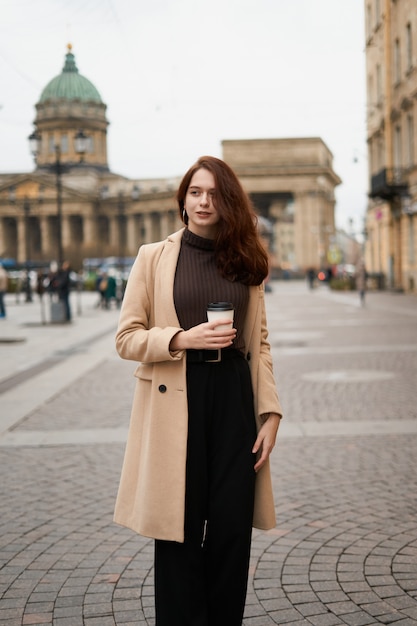 Hermosa chica elegante moda elegante elegante con taza de café en las manos va caminando por la calle