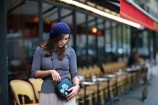 Hermosa chica elegante en París una belleza en una boina azul en el fondo de un café parisino