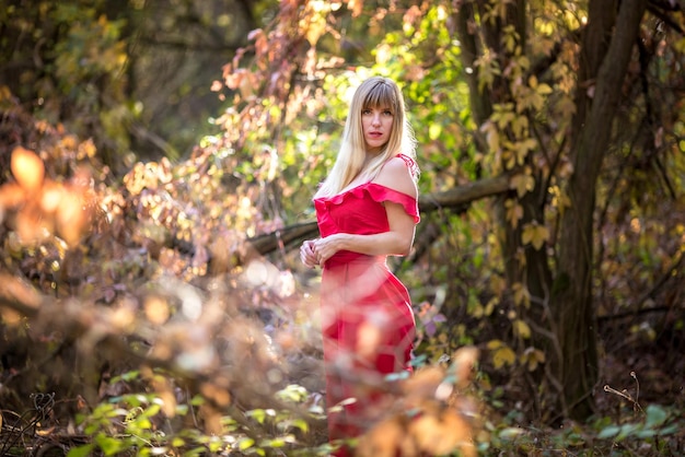 Hermosa chica elfa en vestido rojo en el cuento de hadas de fantasía del bosque del bosque de otoño