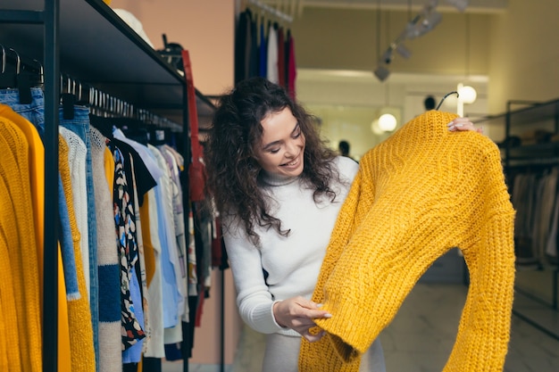 Hermosa chica elige ropa en una boutique