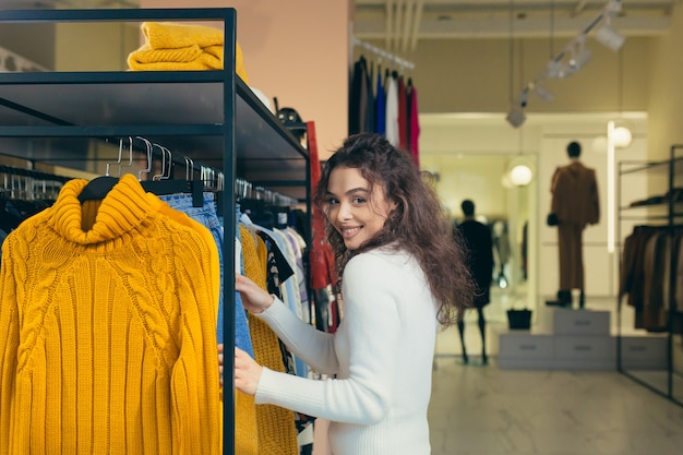 Hermosa chica elige ropa en una boutique